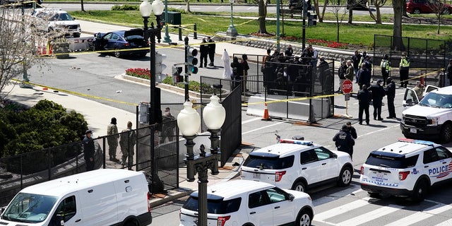 Police officers gather near a car that crashed into a barrier Friday on Capitol Hill in Washington. One Capitol Police officer and a suspect have died. (AP Photo/J. Scott Applewhite)