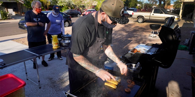 Chef Mike Winneker prepares tacos in front of his home Saturday, April 3, 2021, in Scottsdale, Ariz. Beaten down by the pandemic, many laid-off or idle restaurant workers have pivoted to dishing out food with a taste of home. Some have found their entrepreneurial side, slinging their culinary creations from their own kitchens. (AP Photo/Ross D. Franklin)