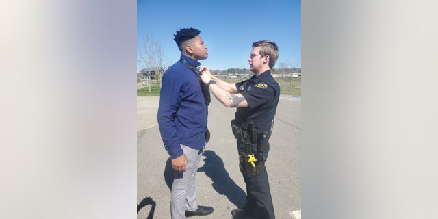 Officer Adam Price helps 18-year-old Jalen Lewis tie a tie.