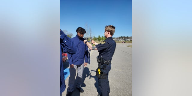 Officer Adam Price helps 18-year-old Elijah Darling tie a tie.