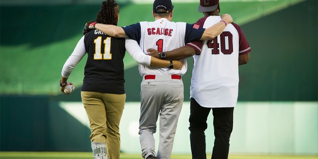 Capitol Police Special Agents Crystal Griner, left, and David Bailey, right, assist U.S. Rep. Steve Scalise to his position at second base at the start of the 57th Congressional Baseball Game at National's Park in Washington, Thursday, June 14, 2018.