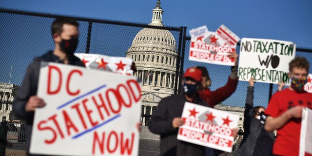 Activists hold signs as they take part in a rally in support of DC statehood near the US Capitol in Washington, DC on March 22, 2021. - Democrats emboldened by their control of the US House, Senate and White House launched a fresh push Monday for statehood for the nation's capital Washington, beginning with a high-profile congressional hearing addressing the issue. (Photo by MANDEL NGAN / AFP) (Photo by MANDEL NGAN/AFP via Getty Images)