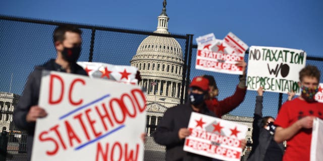 Activists hold signs as they take part in a rally in support of DC statehood near the US Capitol in Washington, DC on March 22, 2021. - Democrats emboldened by their control of the US House, Senate and White House launched a fresh push Monday for statehood for the nation's capital Washington, beginning with a high-profile congressional hearing addressing the issue. (Photo by MANDEL NGAN / AFP) (Photo by MANDEL NGAN/AFP via Getty Images)