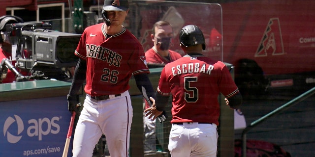 Arizona Diamondbacks' Eduardo Escobar (5) celebrates his run scored against the Cleveland Indians with Diamondbacks' Pavin Smith (26) during the fourth inning of a spring training baseball game Tuesday, March 30, 2021, in Phoenix. (AP Photo/Ross D. Franklin)