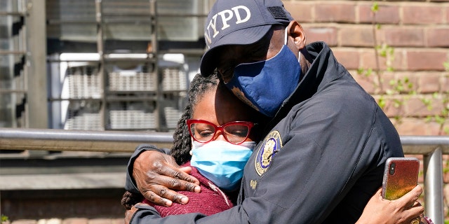 On Tuesday, April 6, 2021, a police officer hugged a community leader outside the building. A man shot and killed his child's mother and two daughters before turning on himself. (AP Photo/Mary Altaffer)