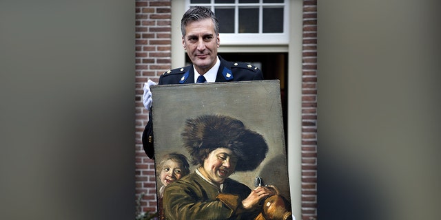 This photograph taken on November 3, 2011, shows District Chief of Alblasserwaard, Bart Willemsen showing the recovered painting "Two Laughing Boys" by Frans Hals which was stolen from the Leerdam Museum in May 2011. (Photo by ILVY NJIOKIKTJIEN/ANP/AFP via Getty Images)