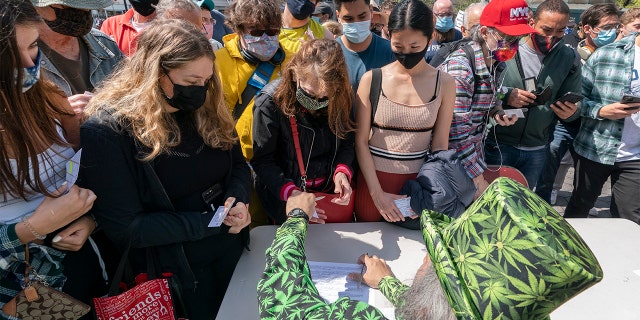 A man wearing a cannabis costume hands out marijuana cigarettes in New York during a "Joints for Jabs" event, where adults who showed their COVID-19 vaccination cards received a free joint. (AP Photo/Mark Lennihan, File)