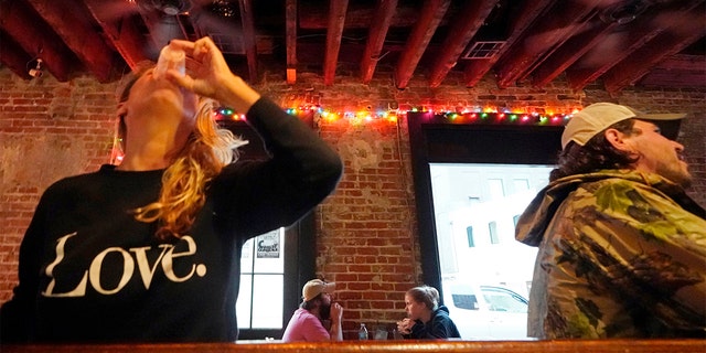 In this Tuesday, April 13, 2021 file photo, Allison Richter drinks her free shot at the bar, after receiving the Moderna COVID-19 vaccine, during a vaccine event. (AP Photo/Gerald Herbert)