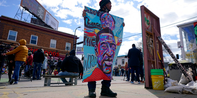 A man holds a sign at George Floyd Square, Wednesday, April 21, 2021, in Minneapolis, a day after former Minneapolis police Officer Derek Chauvin was convicted on all counts for the 2020 death of Floyd.
