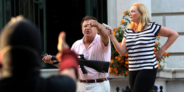 Armed homeowners Mark and Patricia McCloskey stand outside their house as they confront protesters marching to St. Louis Mayor Lyda Krewson's house Sunday, June 28, 2020. (Getty Images)