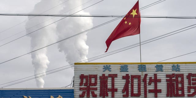The Chinese flag flies in front of exhaust rising from a coal-fired power plant in Jiayuguan, Gansu province, China, April 1, 2021.