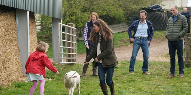 Catherine, Duchess of Cambridge and farmer's daughter Clover Chapman, 9, walk a lamb together, watched by her parents and Prince William, Duke of Cambridge, during a royal visit to Manor Farm in Little Stainton, Durham on April 27, 2021, in Darlington, England.