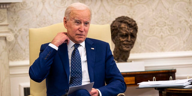 President Biden tugs at shirt collar while in White House.