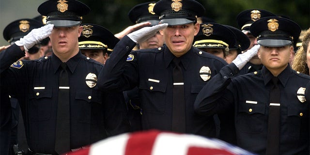 Burbank police officers salute the casket of their slain colleague Matthew Pavelka during funeral services at Forest Lawn Cemetary in Los Angeles Friday. Officer Pavelka was shot and killed while making a routine traffic stop.