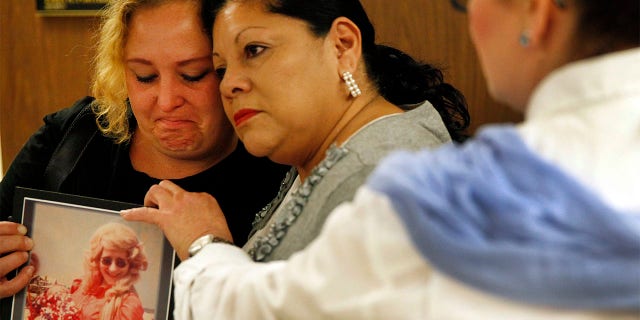 Pearl Nelson (left) is holding a photo of her mother, victim Audrey Nelson, as she is hugged by Mary Louise Frias, whose godmother, Guadalupe Apodaca Zambrano, was also a victim of convicted serial killer Samuel Little.