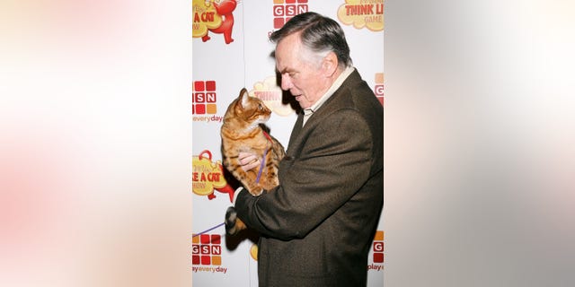 TV personality Peter Marshall holds a cat as he arrives at the Meow Mix Think Like a Cat Game Show Premiere on November 12, 2008, in Los Angeles, California. 