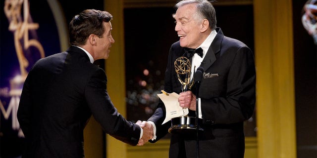 Mike Richards (left) accepts the Outstanding Game Show award for 'The Price is Right' from Peter Marshall onstage during the 45th annual Daytime Emmy Awards at Pasadena Civic Auditorium on April 29, 2018, in Pasadena, California.