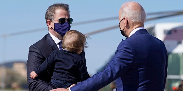 President Joe Biden talks with his son Hunter Biden as he holds his grandson Beau Biden as they walk to board Air Force One at Andrews Air Force Base, Md., Friday, March 26, 2021. (AP Photo/Patrick Semansky)