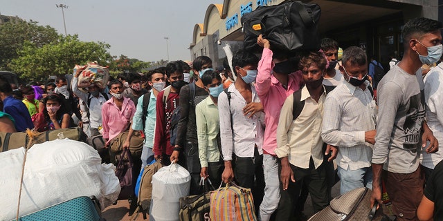 April 14, 2021: People wearing masks as a precaution against the coronavirus stand in queues to board trains at Lokmanya Tilak Terminus in Mumbai.