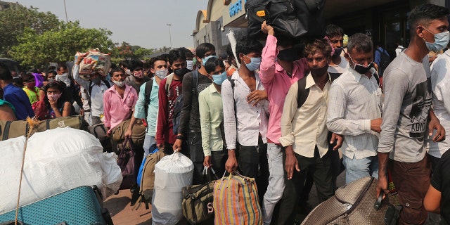 April 14, 2021: People wearing masks as a precaution against the coronavirus stand in queues to board trains at Lokmanya Tilak Terminus in Mumbai.