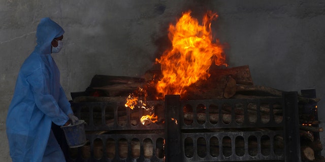 April 15, 2021: A municipal worker in personal protective suit performs last rites during the cremation of a COVID-19 victim in Vasai, on the outskirts of Mumbai, India.