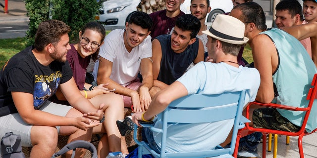 Youths gather on a street in the Israeli coastal city of Tel Aviv on April 18, 2021, after authorities announced that face masks for COVID-19 prevention were no longer needed outside. (Photo by JACK GUEZ/AFP via Getty Images)