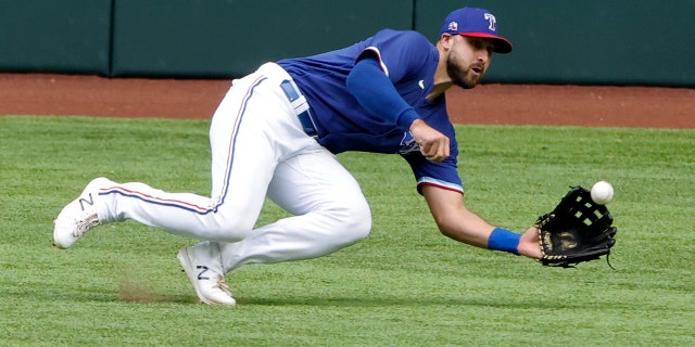 Texas Rangers center fielder Joey Gallo makes a diving catch against the Milwaukee Brewers during the third inning of a preseason baseball game Tuesday, March 30, 2021, in Arlington, Texas. (AP Photo/Michael Ainsworth)