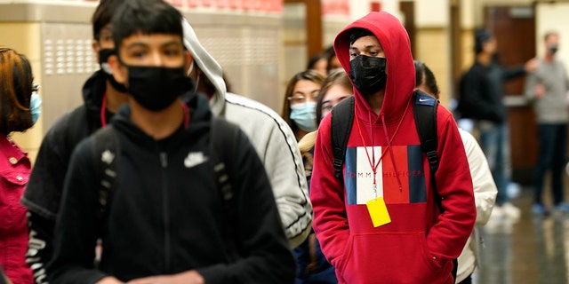 FILE - In this March 31, 2021, file photo, students at Wyandotte County High School wear masks as the walk through a hallway on the first day of in-person learning at the school in Kansas City, Kan. (AP Photo/Charlie Riedel, File)