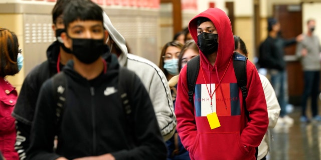 FILE - In this March 31, 2021, file photo, students at Wyandotte County High School wear masks as the walk through a hallway on the first day of in-person learning at the school in Kansas City, Kan. (AP Photo/Charlie Riedel, File)