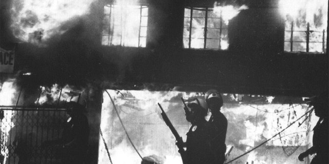 Police officers stand watch over burning building in West Los Angeles following looting and arson reaction to the acquittal of four LAPD officers in the Rodney King incident. 