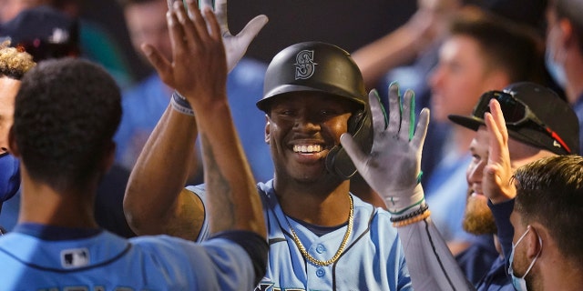 Seattle Mariners' Kyle Lewis, center, celebrates his solo home run with teammates in the dugout during the third inning of a spring training baseball game against the Chicago White Sox, Friday, March 19, 2021, in Peoria, Ariz. (AP Photo/Sue Ogrocki)