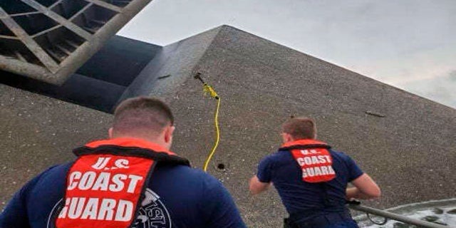 Coast Guard Station Grand Isle 45-foot Response Boat-medium boat crew members attempt to throw a hammer Thursday at the hull of the SeaCor Power. The crew was attempting to make contact with potential survivors inside the vessel. (AP/U.S. Coast Guard)