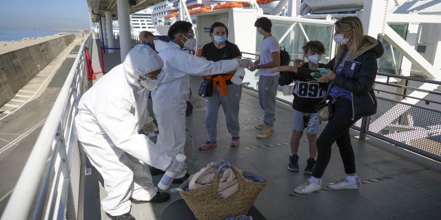 Passengers have their hand luggage sanitized prior to boarding the MSC Grandiosa cruise ship in Civitavecchia, near Rome, Wednesday, March 31, 2021. (AP Photo/Andrew Medichini)