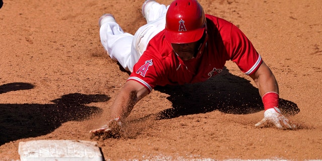 Los Angeles Angels' Mike Trout dives back safely on a pick-off attempt during the fifth inning of a spring training baseball game against the Milwaukee Brewers, Thursday, March 18, 2021, in Tempe, Ariz. (AP Photo/Matt York)