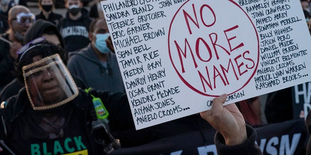 A protester holds up a placard with the names of people who died during police incidents, during a protest over the fatal shooting of Daunte Wright during a traffic stop, in front of the Brooklyn Center Police Department, Friday, April 16, 2021, in Brooklyn Center, Minnesota. . (Associated Press)
