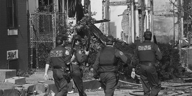 Several Philadelphia police officers patrol the West Philadelphia neighborhood destroyed by the bombing of the MOVE headquarters in 1985.