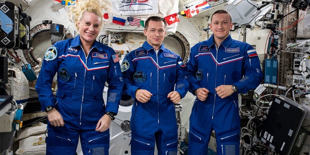 Trojčlenná posádka 64 expedície z JAXA (Japonská agentúra pre prieskum kozmického priestoru).  Zľava sú Kate Rubins z NASA, Sergey Reznikov z Roskosmosu a Sergej Kud-Severchkov z Roskosmosu.