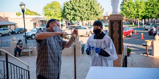 Eucharistic Minister Ron Limon (L) and Altar Server Christopher Coker, 12, prepare for a mass outside of the Basilica of San Albino in which communion would be given to parishioners on May 2, 2020 in Mesilla, New Mexico. (Photo by PAUL RATJE/AFP via Getty Images)