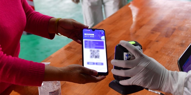  medical worker scans QR code on the mobile phone screen for registration before a resident receives nucleic acid testing for COVID-19 at Munao community, Ruili City, southwest China's Yunnan Province, April 6, 2021. (Xinhua/Chen Xinbo via Getty Images)