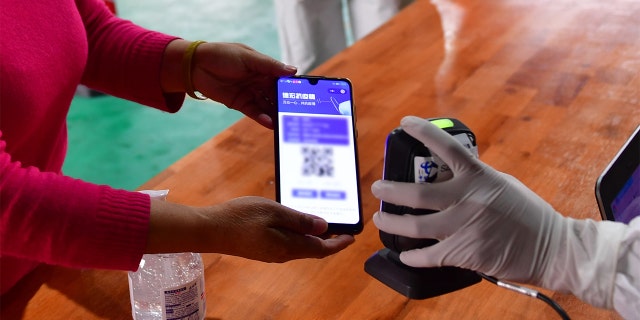  medical worker scans QR code on the mobile phone screen for registration before a resident receives nucleic acid testing for COVID-19 at Munao community, Ruili City, southwest China's Yunnan Province, April 6, 2021. (Xinhua/Chen Xinbo via Getty Images)