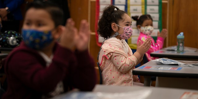 First graders applaud while listening to their teach in a classroom on the first day of in-person learning at Heliotrope Avenue Elementary School in Maywood, California, Tuesday, April 13, 2021. (AP Photo/Jae C. Hong)