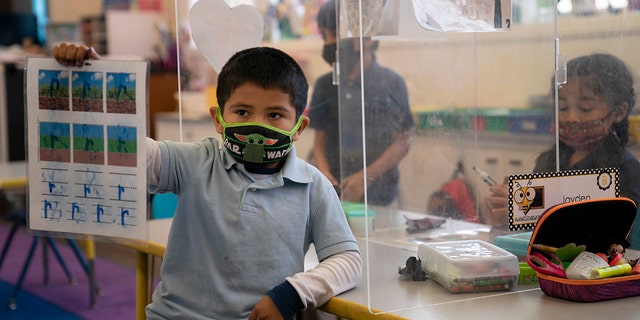 FILE - In this March 18, 2021, file photo, Cesar Verdugo, 5, shows his work to his teacher in a pre-kindergarten class at West Orange Elementary School in Orange, Calif. (AP Photo/Jae C. Hong, File)