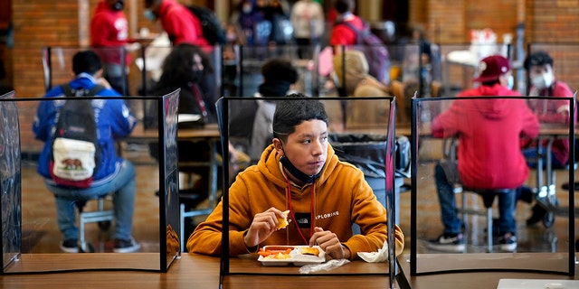 Freshman Hugo Bautista eats lunch separated from classmates by plastic dividers at Wyandotte County High School in Kansas City, Kan., on the first day of in-person learning. (AP Photo/Charlie Riedel, File)