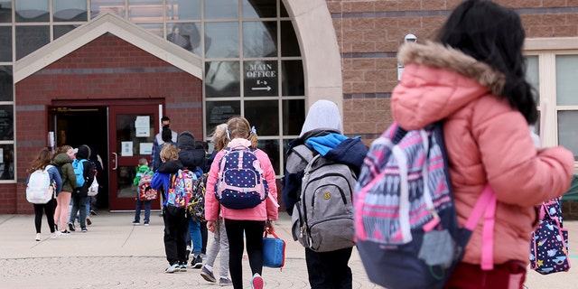 Girls and boys head into the Beebe School, in Malden, Massachusetts, on April 5, 2021, as they return to full-time in-person school. 