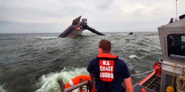 Sur cette photo fournie par la garde côtière américaine, un membre de l'équipage d'un bateau moyen de bateau d'intervention de 45 pieds de la station de la Garde côtière de Grand Isle recherche des survivants près du SeaCor Power chaviré.  Le Seacor Power, un navire de l'industrie pétrolière, s'est retourné mardi 13 avril 2021 dans une microrafale de vent dangereux et de haute mer.  (Garde côtière américaine via AP)