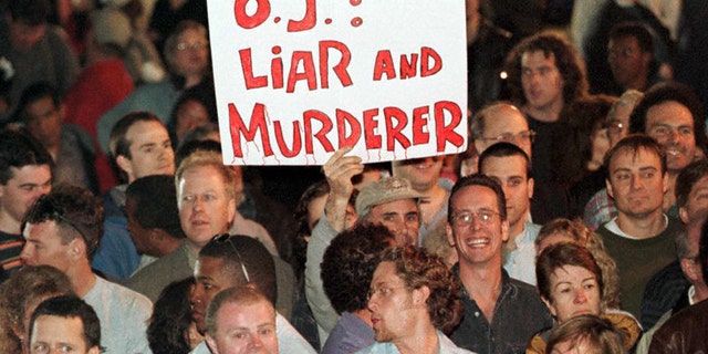 SANTA MONICA, UNITED STATES: Spectators outside the Santa Monica, California, courthouse, hold an-anti O.J Simpson placard as they react to the guilty verdicts in the Simpson wrongful death civil trial 04 February. Simpson was found liable for the deaths of his ex-wife Nicole Brown Simpson and her friend Ron Goldman. (Photo credit should read HECTOR MATA/AFP via Getty Images)