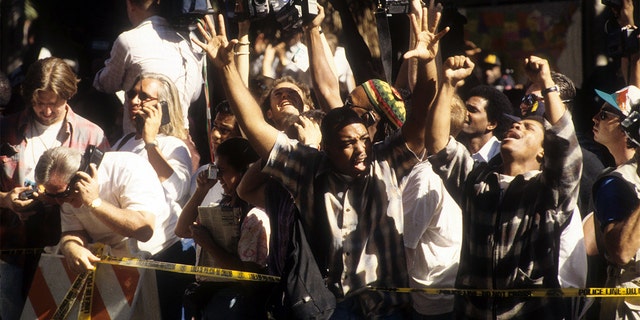 The crowd cheers after hearing the decision of the O.J. Simpson verdict at the Los Angeles Courthouse on October 3, 1995. (Photo by Michael Montfort/Michael Ochs Archives/Getty Images)