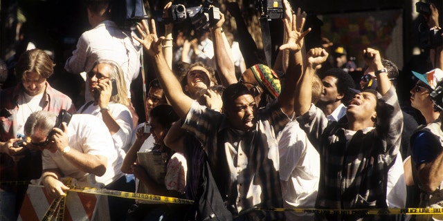 The crowd cheers after hearing the decision of the O.J. Simpson verdict at the Los Angeles Courthouse on October 3, 1995. (Photo by Michael Montfort/Michael Ochs Archives/Getty Images)