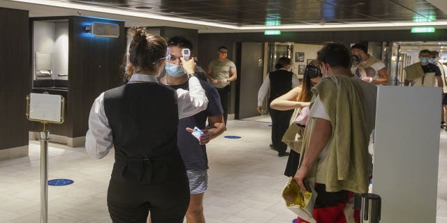 Passengers have their body temperature measured as they enter a restaurant of the MSC Grandiosa cruise ship in Civitavecchia, near Rome, Wednesday, March 31, 2021.(AP Photo/Andrew Medichini)