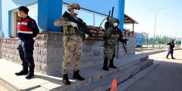 Soldiers stand guard as citizens wait outside court before the trial of 497 defendants in Sincan, Turkey, on Wednesday. (AP)